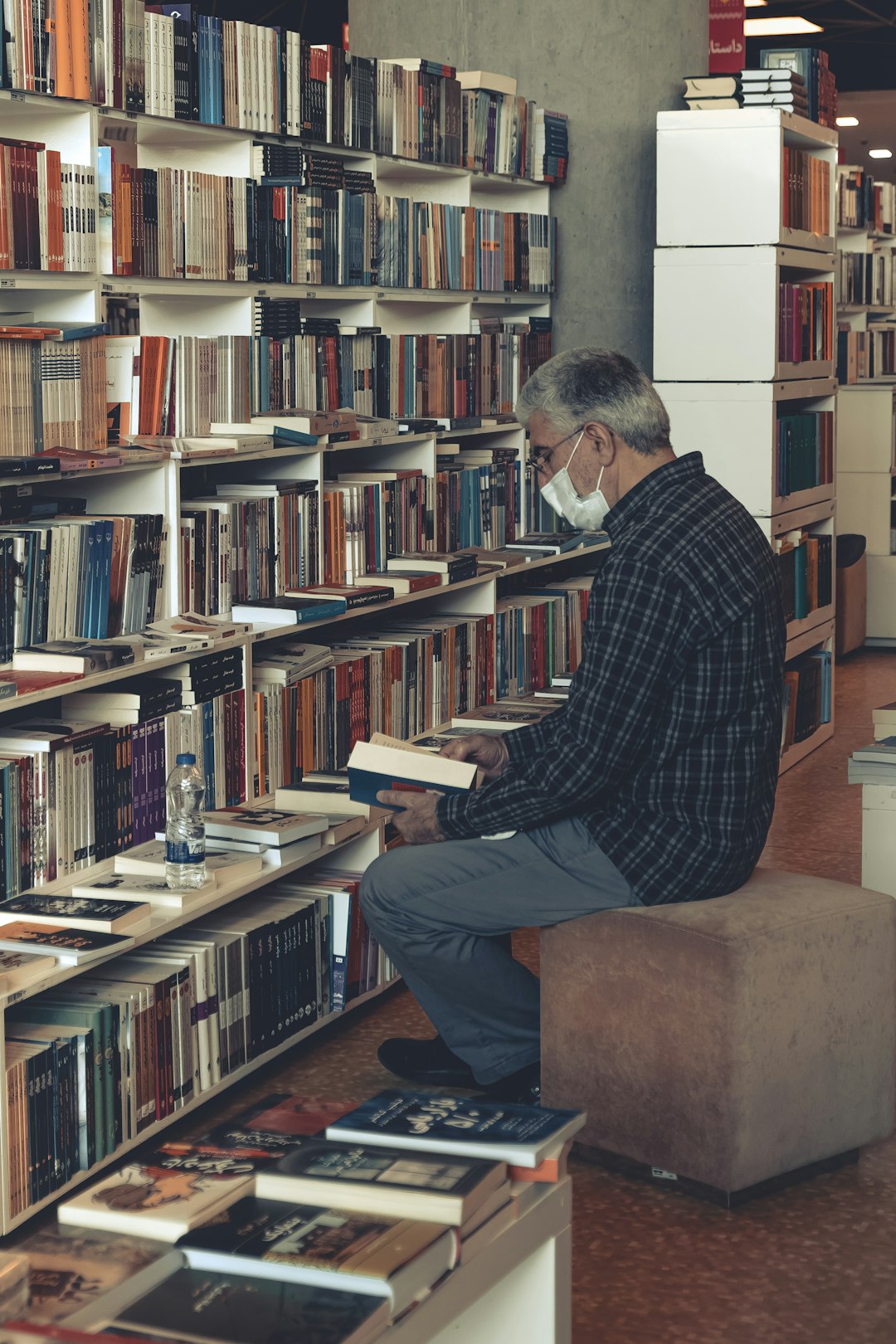 unsplash person reading a book in a library surrounded by books and knowledge pw7cizdbz2e